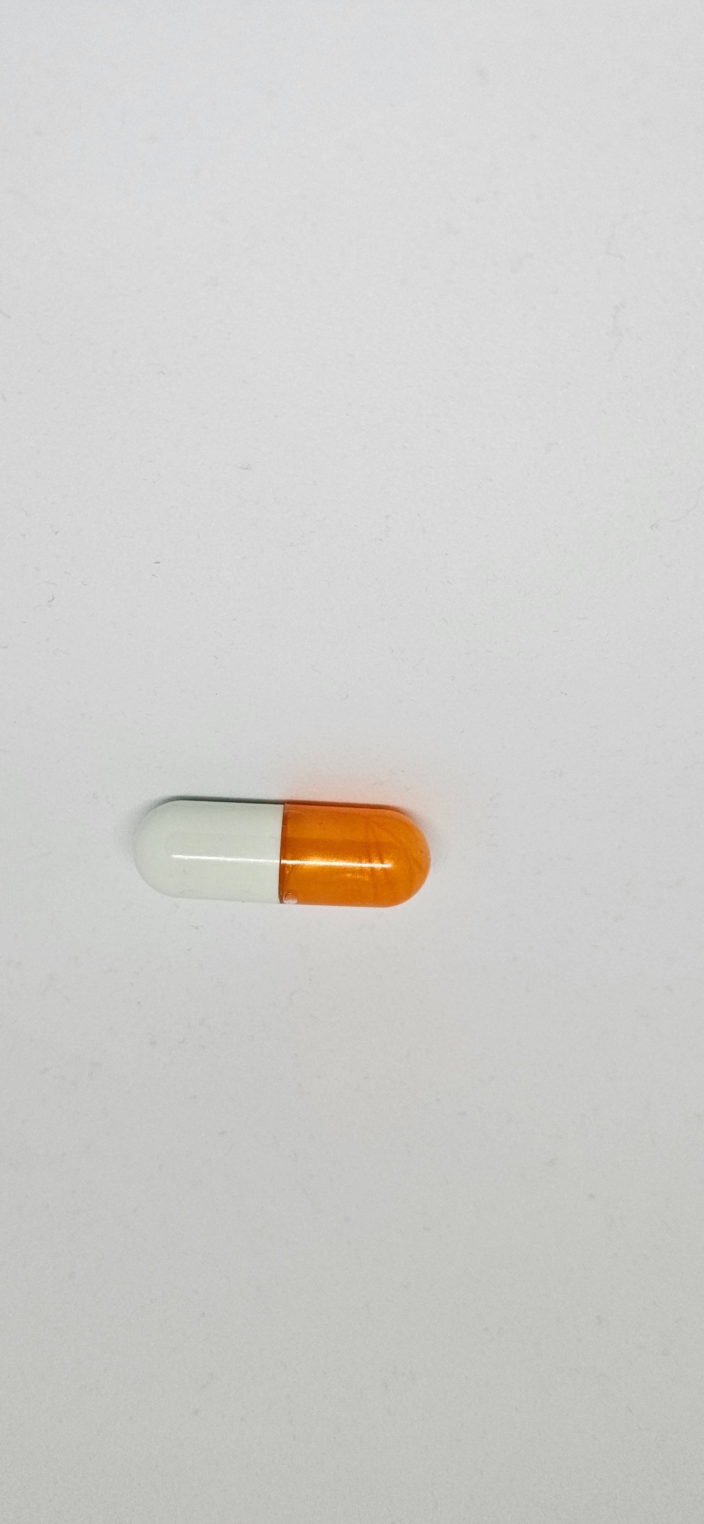 A single orange and white capsule pill against a white background.